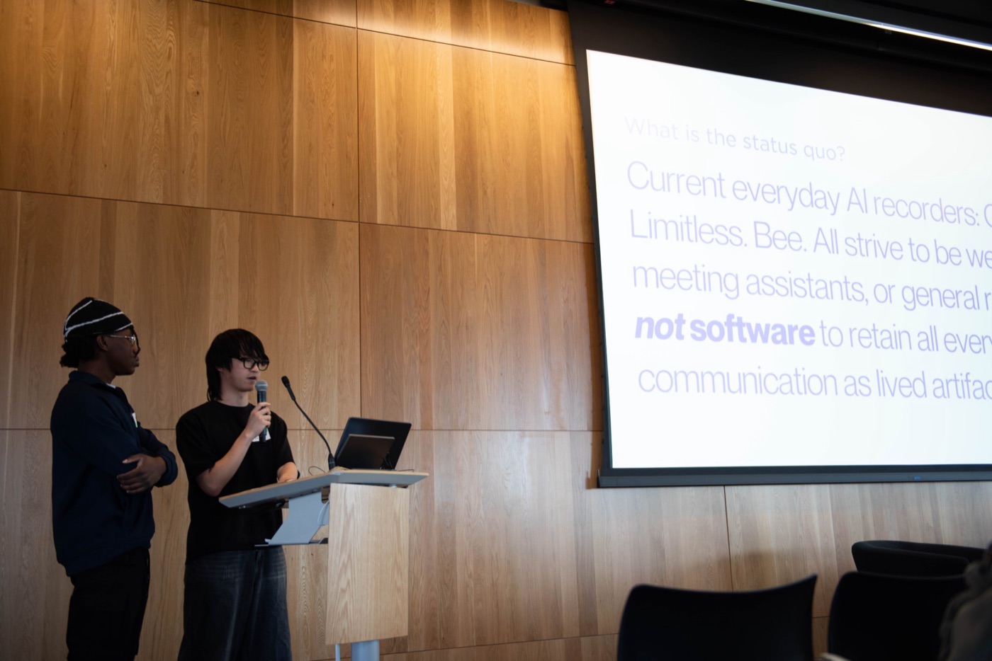 Andrew presenting Onvoice at a podium beside Joshua, in front of a slide about everyday AI recorders